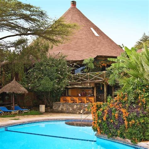 a man standing next to a swimming pool in front of a hut with thatched roof