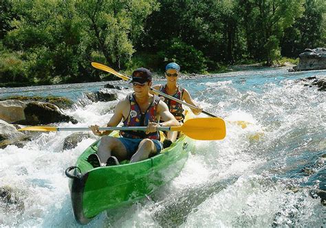 two people in a green canoe paddling down a river