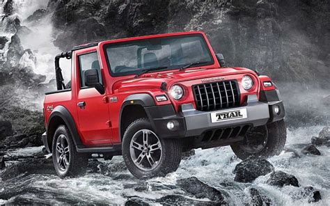 a red jeep is driving through some water