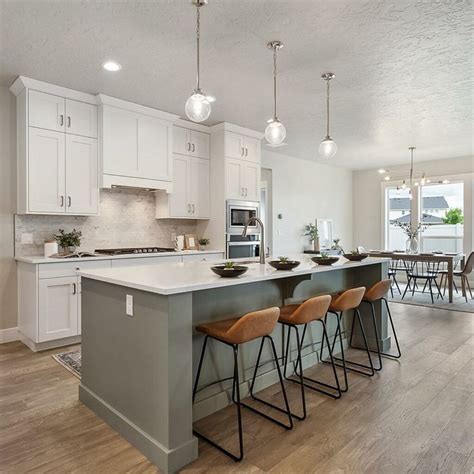 a large kitchen with an island in the middle and four bar stools at the end