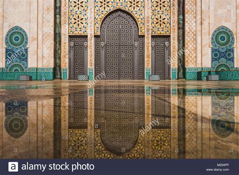 view of Hassan II mosque's big gate reflected on rain water ...