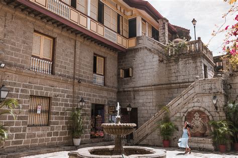 a woman standing in front of an old building next to a fountain with ...