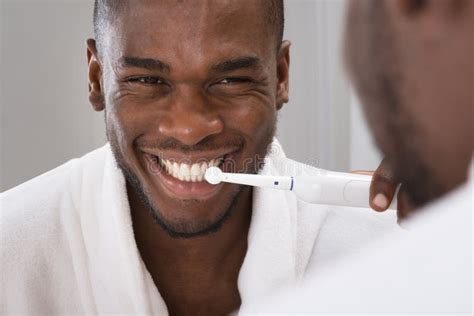 Hombre Africano Que Limpia Sus Dientes En Front of Mirror Imagen de ...