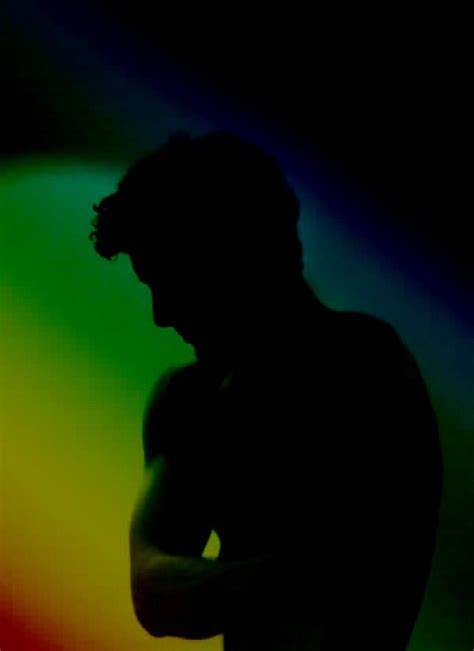 the silhouette of a man standing in front of a rainbow colored ...