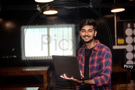 Image of Smiling Young Indian Man working on a Laptop in an office ...