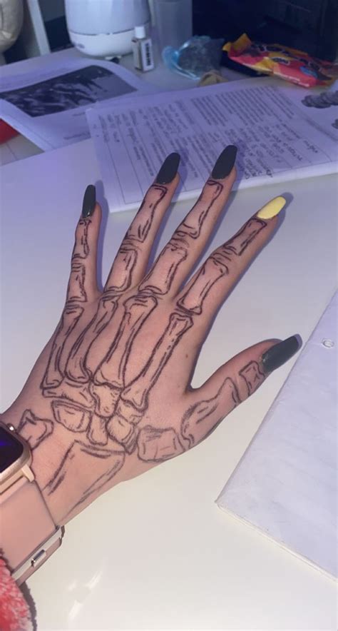 a woman's hand with black and yellow nails is shown on top of a desk