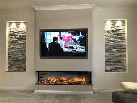 a flat screen tv mounted on the wall above a fireplace with two people ...