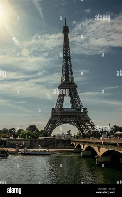 Tourist boat on Seine River, bridge and Eiffel Tower in a sunshine sky ...