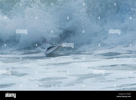 Surfboard appearing from waves after surfer has wiped out Stock Photo ...