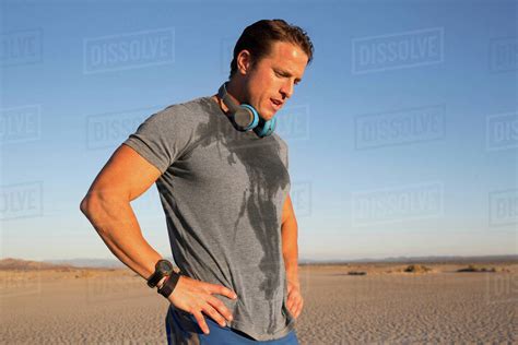 Man training, sweating with hand on hips on dry lake bed, El Mirage ...