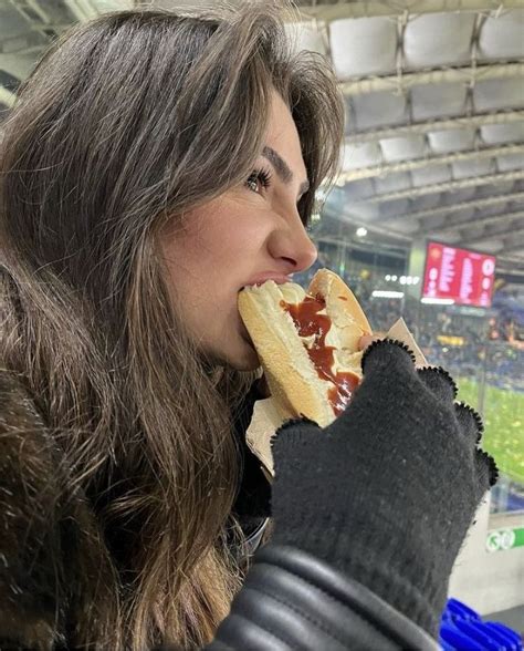 a woman eating a hot dog at a baseball game