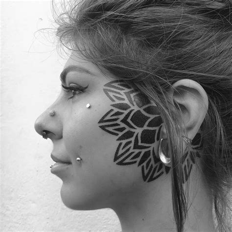 Half mandala tattoo on the face.