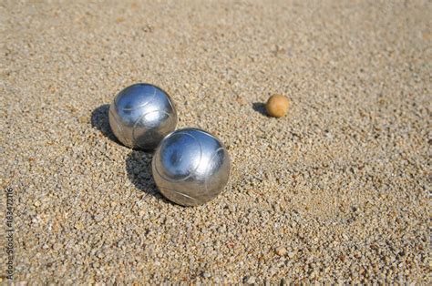 The silver petanque ball is placed between the wooden jack balls on the ...