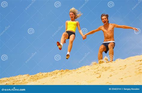 Couple Jumping Off Sand Dune Stock Photo - Image of smiling, blue: 2542314