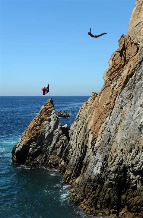 two people jumping off rocks into the ocean from a rocky cliff near an ...