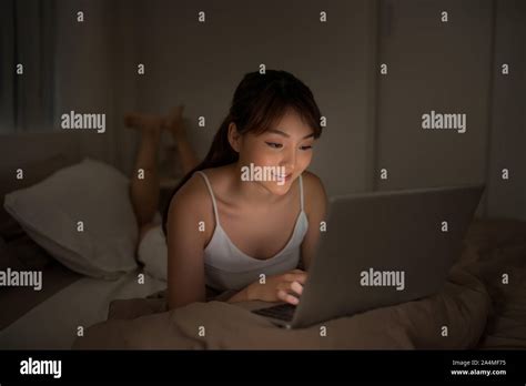 Bedroom evening - woman with laptop lying down in bed Stock Photo - Alamy