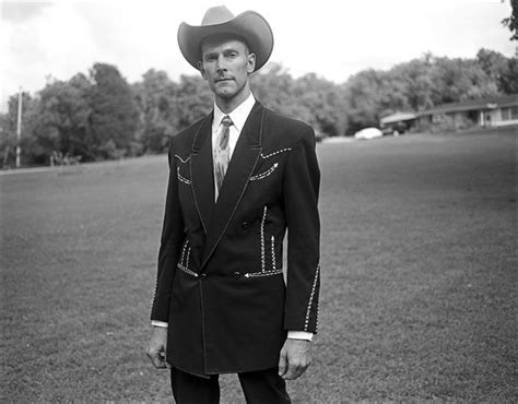 a black and white photo of a man in a suit with a cowboy hat on