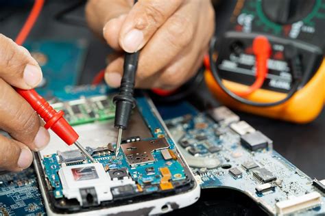 Technician repairing inside of mobile phone by soldering iron ...