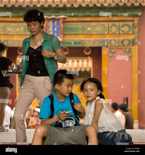 Young Chinese brother and sister sitting in gateway of Forbidden City ...