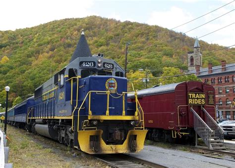 a blue and yellow train traveling down tracks next to a lush green ...