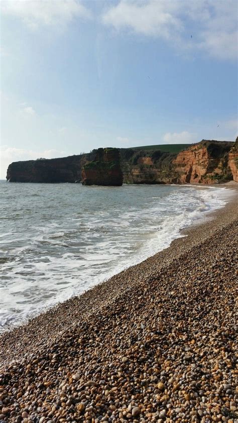 the beach is covered with rocks and pebbles as waves roll in on the ...