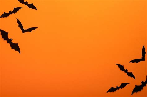 Premium Photo | Orange halloween background flock of black bats for ...