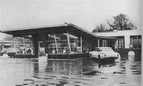 an old black and white photo of a car parked in front of a building on ...