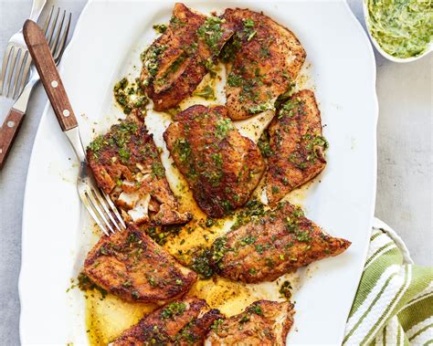 a white plate topped with meat covered in sauce and garnished with parsley