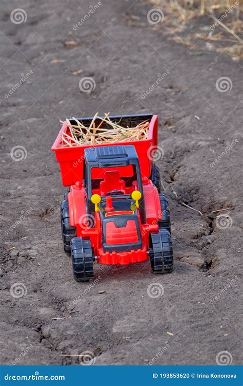 A Red Toy Tractor with a Trailer on a Road Stock Photo - Image of road ...