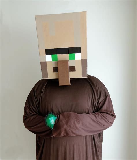 a man in a brown shirt is wearing a minecraft mask and has his hands on ...