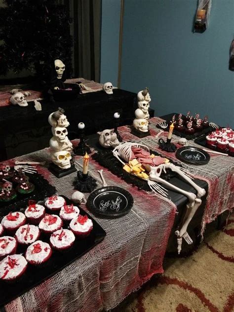 a table topped with cupcakes covered in frosting next to skulls and ...