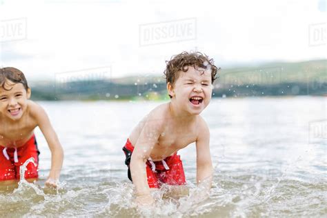 Brothers splashing water in lake - Stock Photo - Dissolve