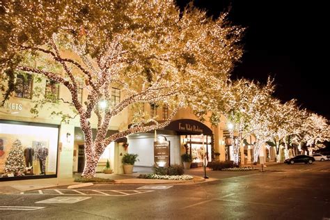 lighted trees line the street in front of shops