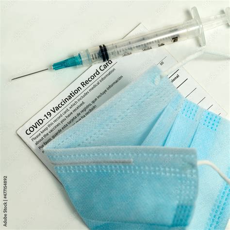 Syringe on Covid-19 vaccination record card and face mask Stock Photo ...