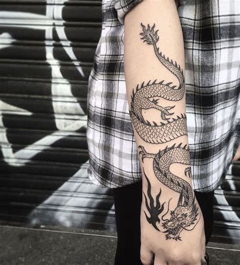 woman wearing black and white shirt, black pants, dragon arm tattoo ...