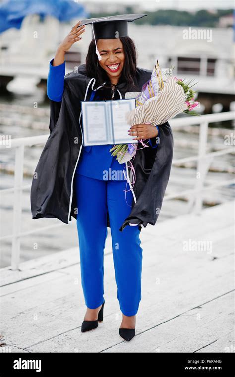 African american student girl in black graduation gown with diploma, at ...