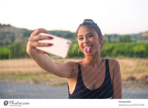 Portrait of teenage girl taking selfie with smartphone while sticking ...