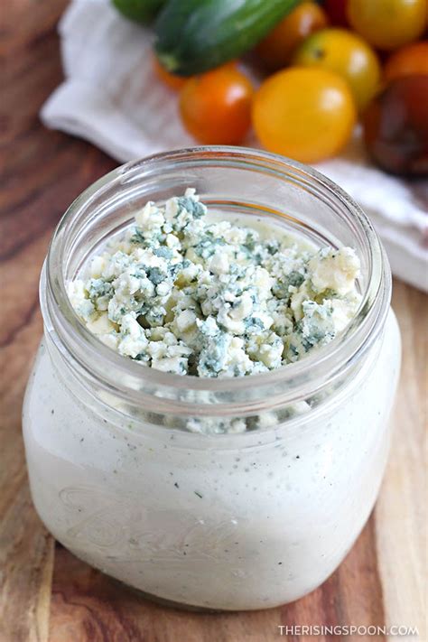 a jar filled with blue cheese sitting on top of a wooden table next to ...