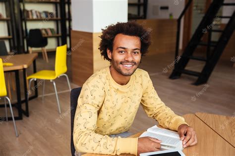 Premium Photo | Portrait of happy young man sitting and studying in library