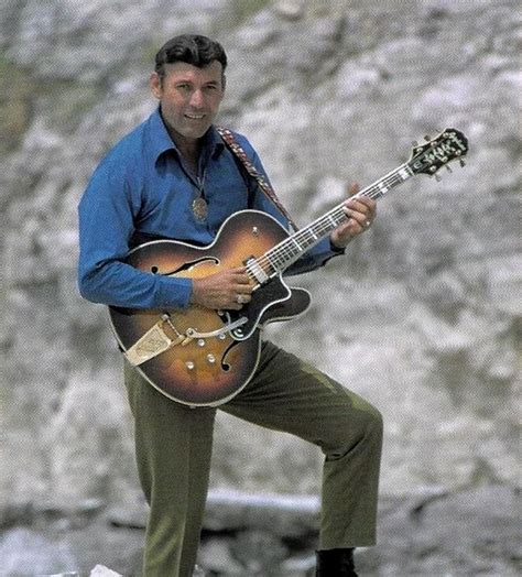 a man playing an electric guitar in front of a rock face with the ...