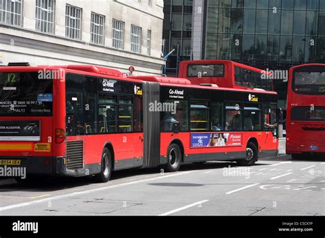 A bendy bus traveling around a stationary double decker bus in London ...