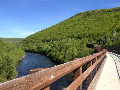 a wooden bridge over a river next to a lush green hillside