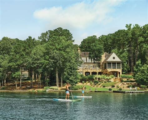 two people on paddle boards in front of a large house and lake with ...