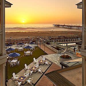 the sun is setting over an oceanfront restaurant with tables and chairs ...