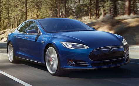 a blue tesla model s is driving down the road in front of some trees ...