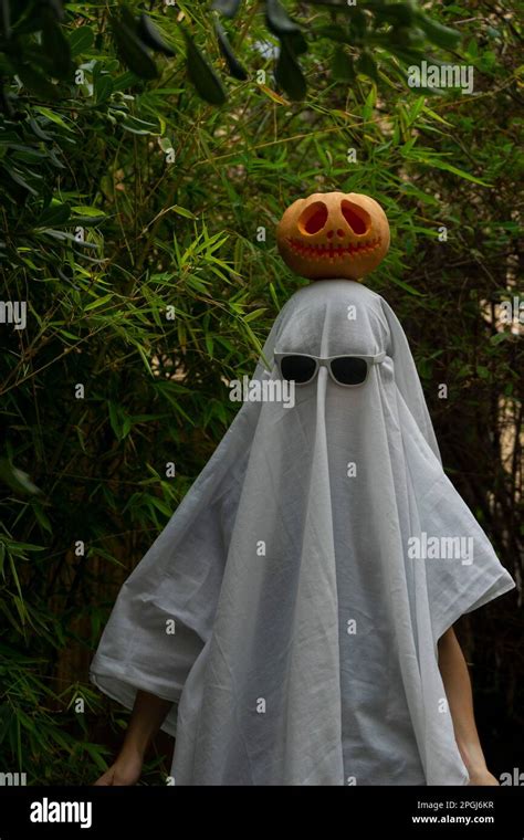 A man dressed in a white ghost costume with sunglasses and a carved ...