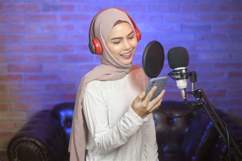 Young Smiling Muslim Female Singer Wearing Headphones with a Microphone ...