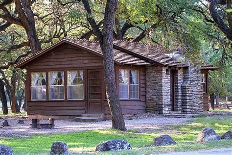 a small cabin in the middle of some trees and grass with rocks around it,