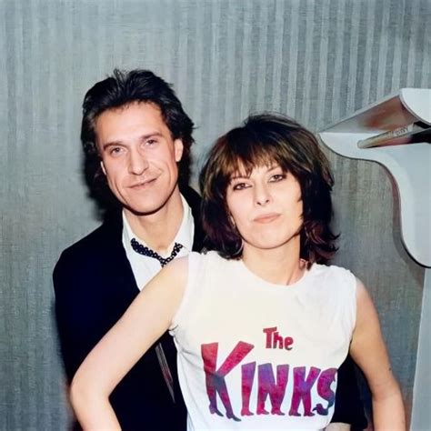 a man and woman standing next to each other in front of a hair dryer