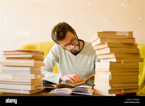 Man studying with a pile of books in front of him Stock Photo - Alamy